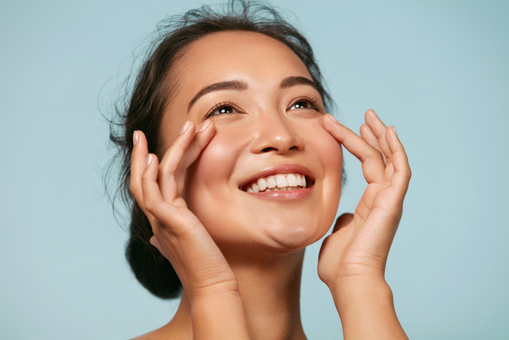 woman touching face and smiling for aesthetic services